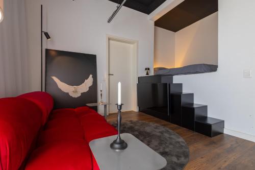 a living room with a red couch and a bed at ETERN Apart-Hotel II in Pristina