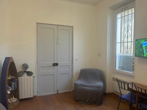 Cette chambre dispose d'une porte et d'une chaise à côté d'une fenêtre. dans l'établissement Studio confortable à Marseille - 25 m² - Proche centre-ville, à Marseille