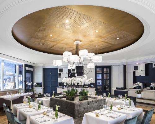 un comedor con mesas blancas y una lámpara de araña en Edouard 7 Paris Opéra, en París