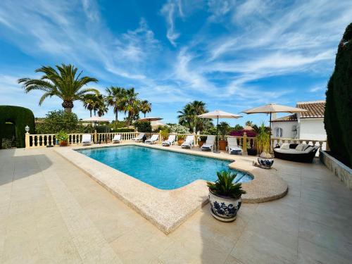 a swimming pool with lounge chairs and umbrellas at Casa Sofia in Calpe