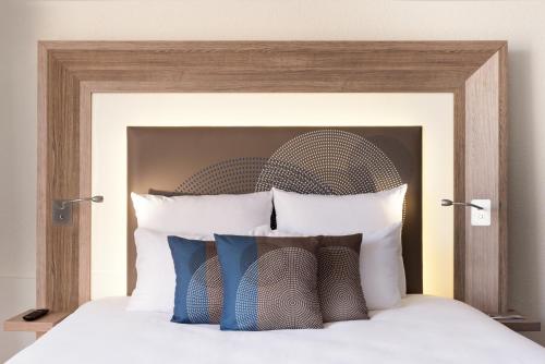 a bed with a wooden head board with pillows at Novotel Genève Centre in Geneva