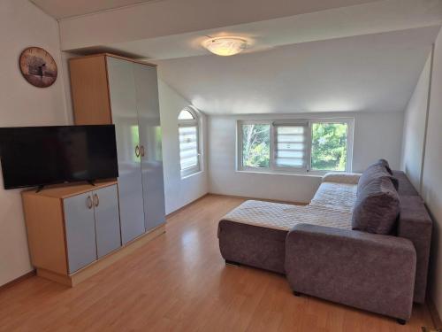 a living room with a couch and a flat screen tv at Apartments Velinka in Rab