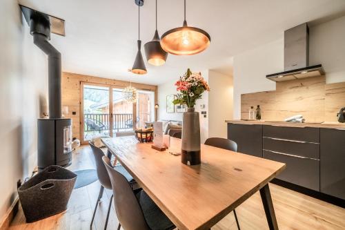 une cuisine et une salle à manger avec une table et des chaises en bois dans l'établissement Apartment Opale Megève - by EMERALD STAY, à Megève