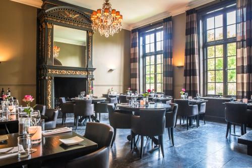 een eetkamer met tafels en stoelen en een kroonluchter bij Fletcher Landgoedhotel Renesse in Renesse