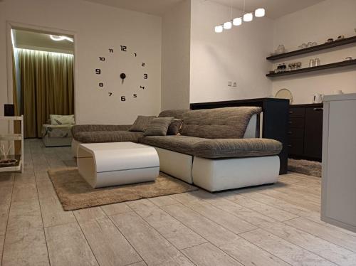 a living room with a couch and a clock on the wall at Cozy apartment with garden in Sarajevo