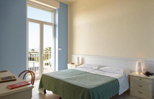 a bedroom with a bed and a large window at Hotel Mirage in Marina di Pietrasanta