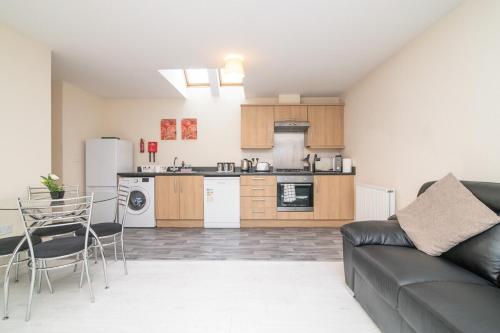 a living room with a couch and a kitchen at Lovely Two Bed detached house with Parking in Tipton