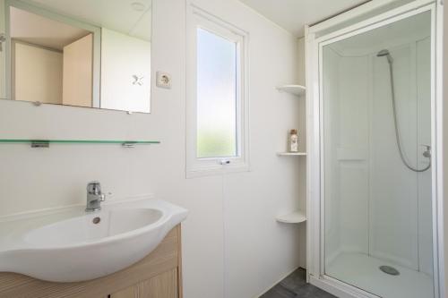 Un baño blanco con lavabo y ducha. en Mobilhome 4 personnes, en Argelès-sur-Mer