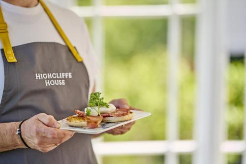 a man holding a plate with food on it at Highcliffe House in Lynton