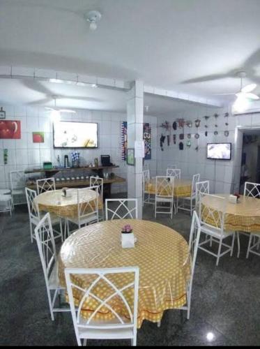 a dining room with tables and chairs with yellow table cloth at Suítes felicidade Rio Centro in Rio de Janeiro