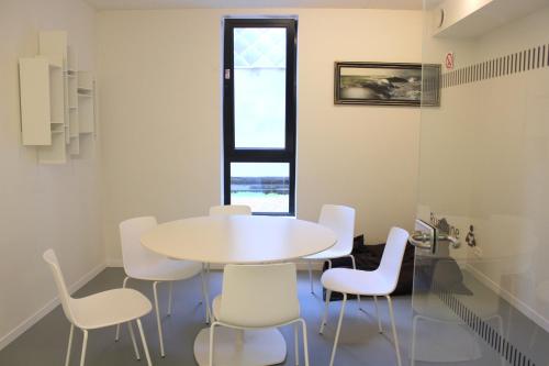 ein weißes Esszimmer mit einem Tisch und weißen Stühlen in der Unterkunft De Ploate Hostel in Ostende