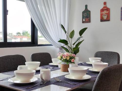 a dining room table with white dishes and flowers on it at Kafaz2-Kpg Patingan 3Bedroom 3 Bathroom -first floor in Kuching