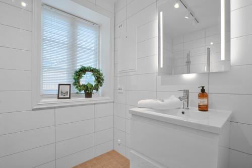a white bathroom with a sink and a window at TotalApartments Skansegata Studio Apartments in Tromsø