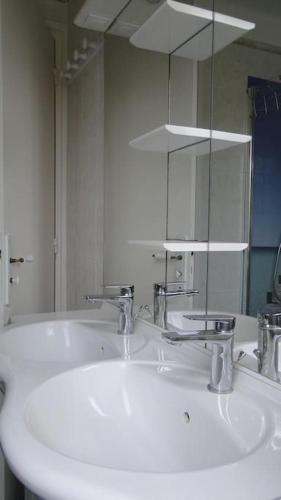 une salle de bain avec un lavabo blanc et un miroir dans l'établissement gite de mer familial, plage et commerces à pied, à Grandcamp-Maisy