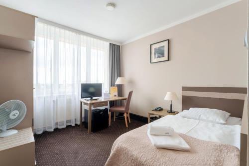 a hotel room with a bed and a desk with a computer at Hotel New Skanpol in Kołobrzeg