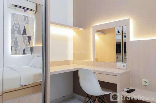 a bedroom with a desk with a mirror and a chair at Cozy and Minimalist Studio (No Kitchen) at Aeropolis Apartment By Travelio in Tangerang