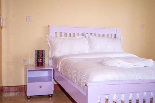a white bed with a night stand next to it at Calmo Meta Homestay Naivasha in Naivasha