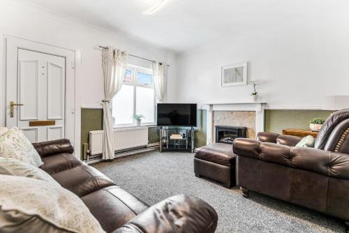 a living room with leather furniture and a television at Modern 2-Bed Home Walk to Ashby Town Centre in Ashby de la Zouch