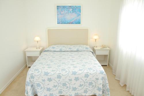 a white bedroom with a bed and two night stands at Aqua Hotel in Punta del Este
