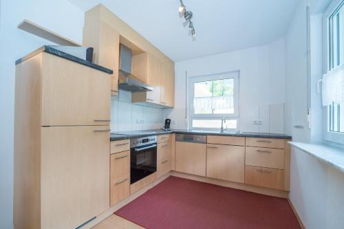 a kitchen with wooden cabinets and a red rug at Apparthaus Schuchter in Silbertal