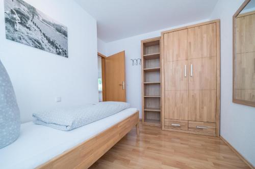 a bedroom with a bed and a wooden cabinet at Apparthaus Schuchter in Silbertal