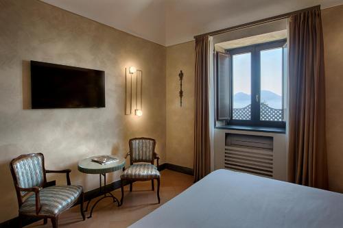 um quarto com uma cama, 2 cadeiras e uma janela em San Francesco al Monte em Nápoles