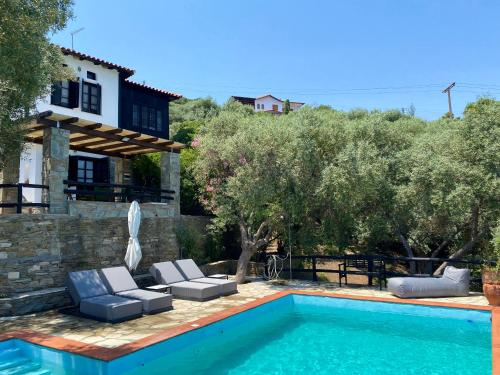 a pool with two lounge chairs and a house at Villa Valia: Traditional Luxurious Residence in Pyrgadikia