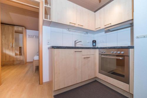 a kitchen with wooden cabinets and a stove top oven at Apparthaus Schuchter in Silbertal