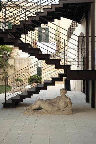 a statue of a man laying on the ground under a staircase at Fiermonte Museum by La Fiermontina in Lecce