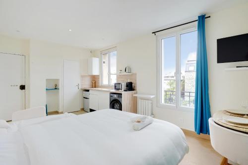 - une chambre blanche avec un lit blanc et une cuisine dans l'établissement Grand studio Aubervilliers, à Aubervilliers