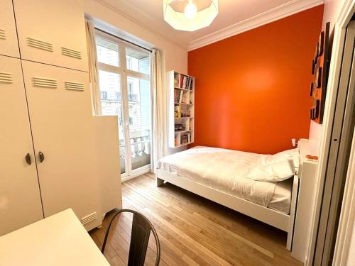 - une petite chambre avec des murs orange et un lit dans l'établissement Grand appartement élégant - Vue Tour Eiffel, à Paris