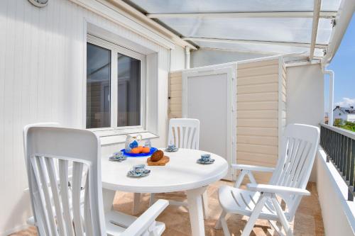 une table blanche et des chaises sur un balcon dans l'établissement Bel appartement - emplacement idéal, à La Barre-de-Monts