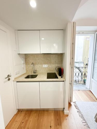 a kitchen with white cabinets and a sink at Largo Inn Suites Evora in Évora