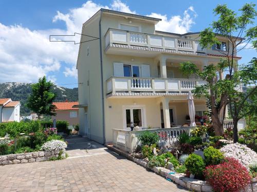 a large white house with a balcony and flowers at Apartments Velinka in Rab