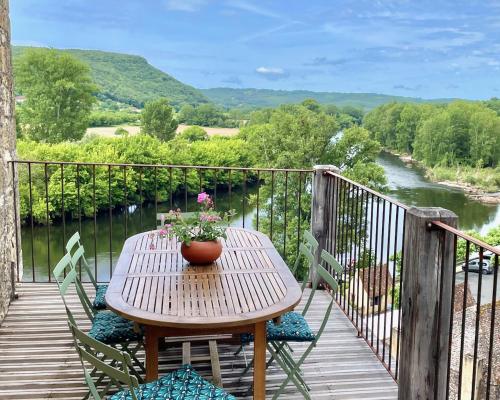 a wooden table with a vase of flowers on a balcony at New Listing! Maison Delluc with Spectacular Vistas in Beynac-et-Cazenac