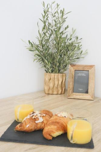a table with bread and orange juice and a plant at La Chambre Passionnée in Wahlbach