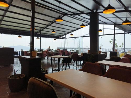 a restaurant with tables and chairs and large windows at Hotel Chail Residency in Chail