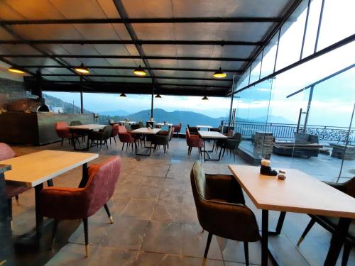 a restaurant with tables and chairs with a view at Hotel Chail Residency in Chail