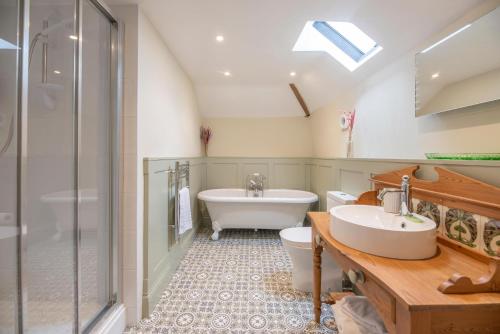 a bathroom with a tub and a toilet and a sink at Harvest Cottage Valley Farm Barns, Snape in Saxmundham