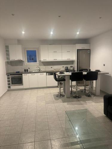 a kitchen with white cabinets and a table and chairs at Casa Nostra Mykonos Boutique Rooms & Studios in Glastros