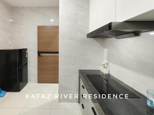 a kitchen with a black refrigerator and white tiles at Kafaz2-Kpg Patingan 3Bedroom 3 Bathroom -first floor in Kuching