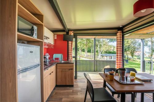 une cuisine et une salle à manger avec une table et un réfrigérateur dans l'établissement Gîte l'Albâtre, à Quiberville