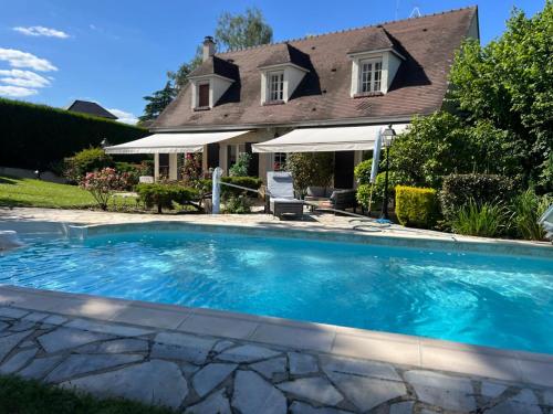 a swimming pool in front of a house at Villa proche Paris et Versailles in Orgeval