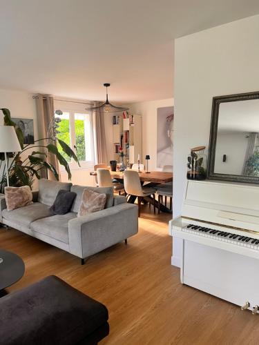 a living room with a couch and a white piano at Villa proche Paris et Versailles in Orgeval