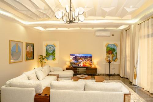 a living room with two white couches and a tv at Résidence La Perle - Yaoundé in Yaoundé