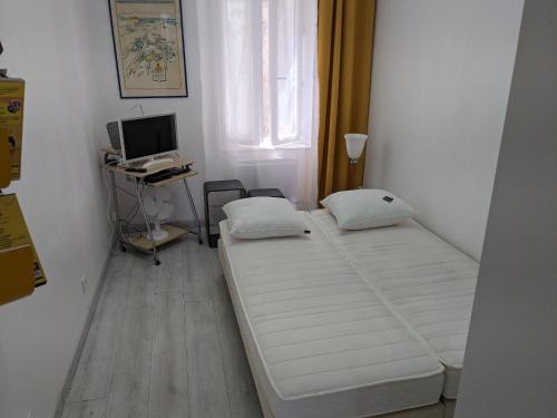 Cette petite chambre comprend un lit et un bureau avec un ordinateur. dans l'établissement joli studio T2 meublé de 20 m² Située à 2 minutes à pied du MÉTRO, à Marseille
