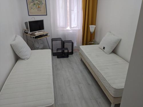 une chambre avec deux lits et un bureau avec un ordinateur dans l'établissement joli studio T2 meublé de 20 m² Située à 2 minutes à pied du MÉTRO, à Marseille