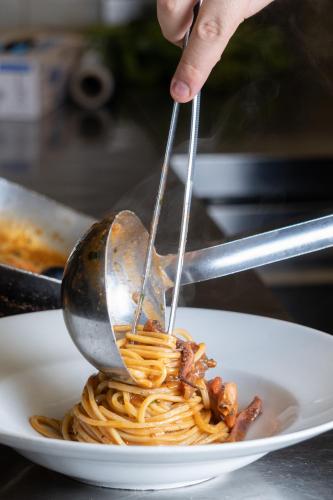a person using tongs to eat spaghetti on a plate at Hotel Isola Sacra Rome Airport in Fiumicino
