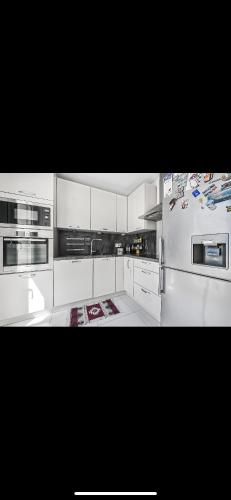une grande cuisine avec des armoires et des appareils blancs dans l'établissement Appartement duplex en résidence familiale et surveillée de 2 chambres à deux pas de paris avec sa place de parking et son jardinet Pas de fêtes, à Bagneux