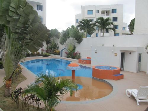 una piscina con palmeras y un edificio en Escapaditas a la Playa, en Tonsupa